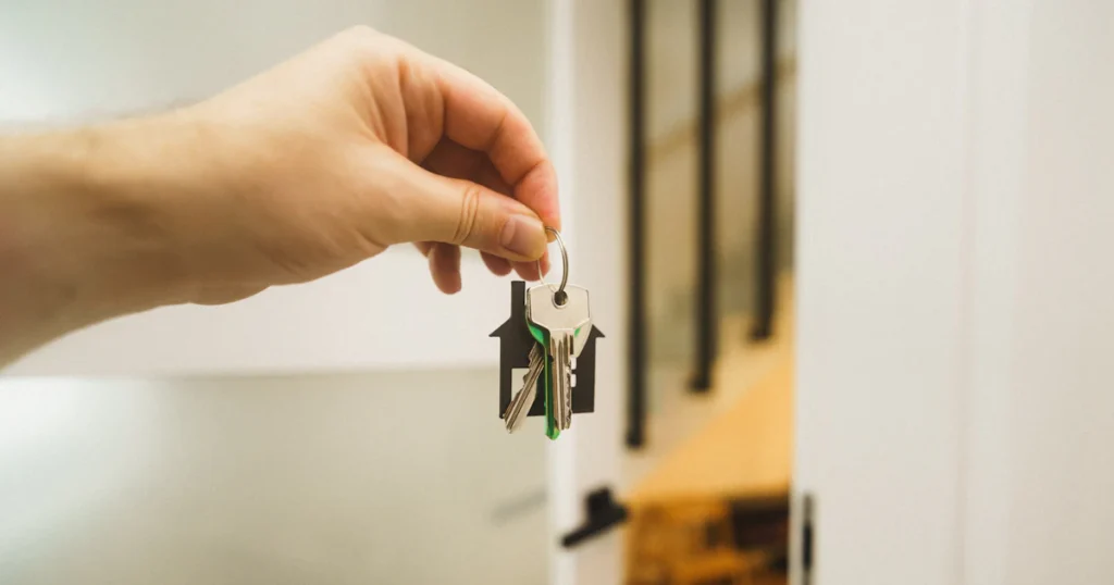 Hand met een huissleutel bij de voordeur van een woning