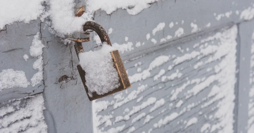 Hangslot op een houten deur, bedekt met sneeuw en vorst