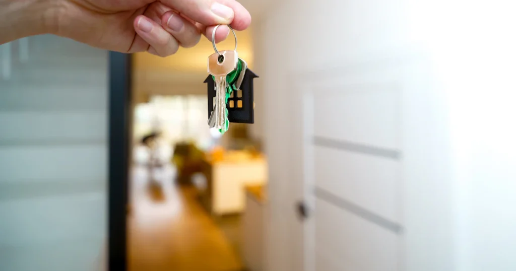 Hand met de sleutelbos van een nieuwe woning in de deuropening